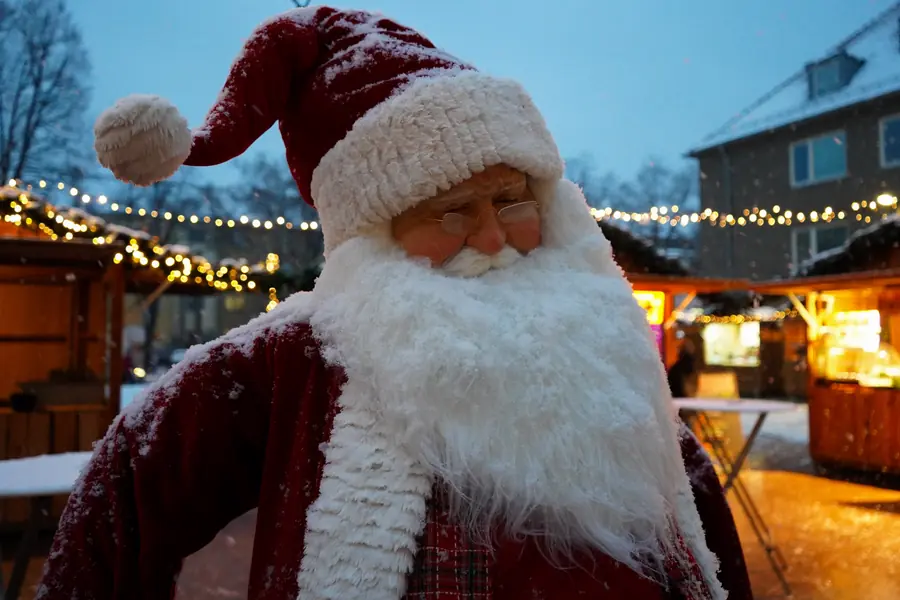 Weihnachtsmann-Figur im Schneegestöber vor den Hütten