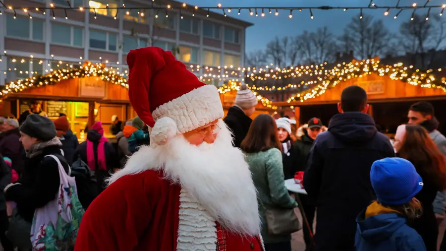 Weihnachtsmann-Figur mitten im Gedränge vor den beleuchteten Hütten
